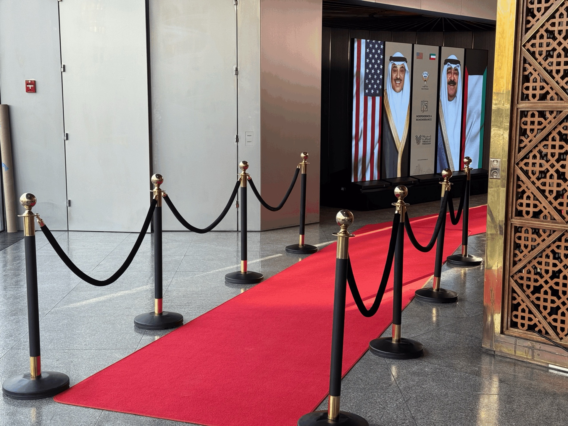 Red-carpet arrival walkway leading to LED welcome displays at the Kuwait Embassy national celebration in Washington, DC