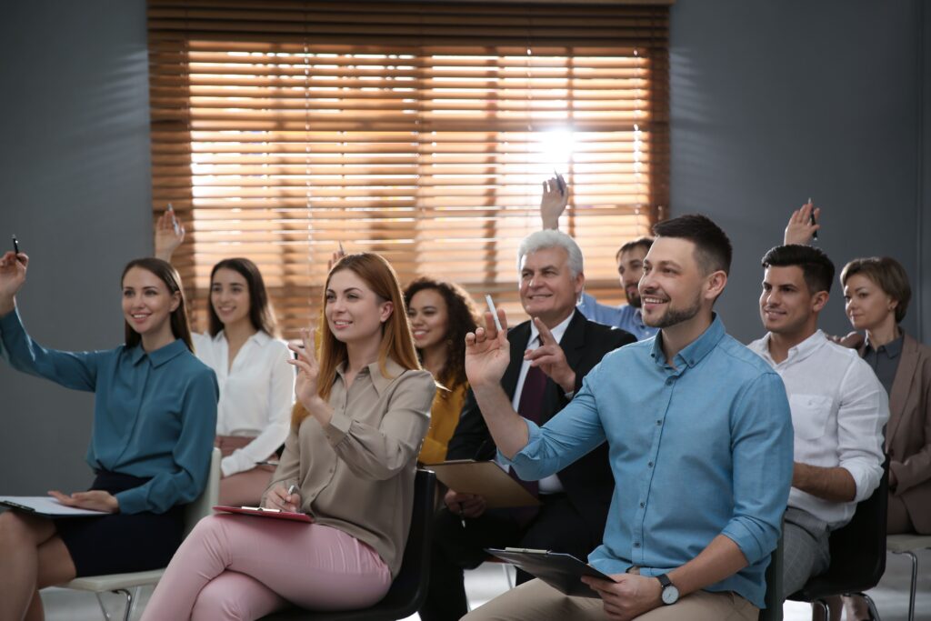 People raising hands to ask questions at seminar i