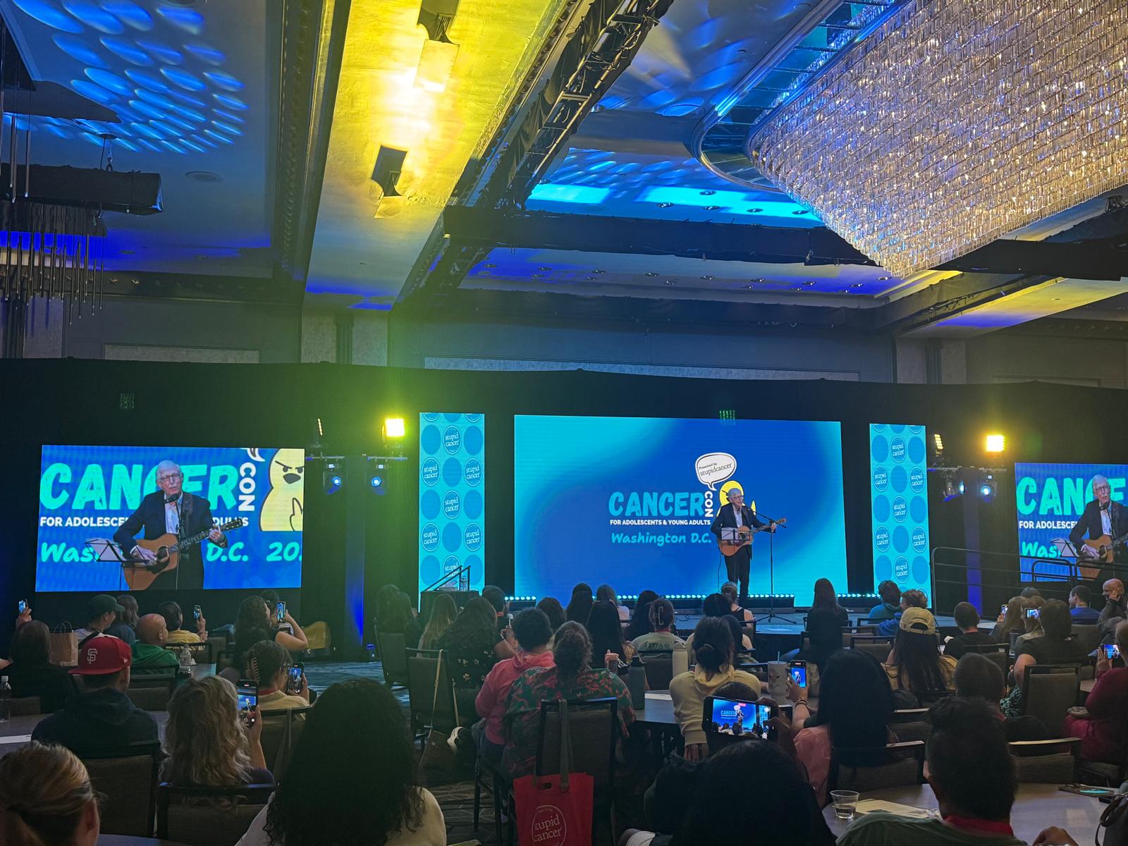 Main-stage LED wall and side IMAG screens during a CancerCon general session in Washington, DC, with a full ballroom audience