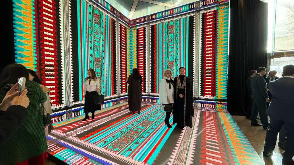 Guests inside an immersive LED room with woven-textile patterns across the walls and floor at a Kuwait Banking Association event